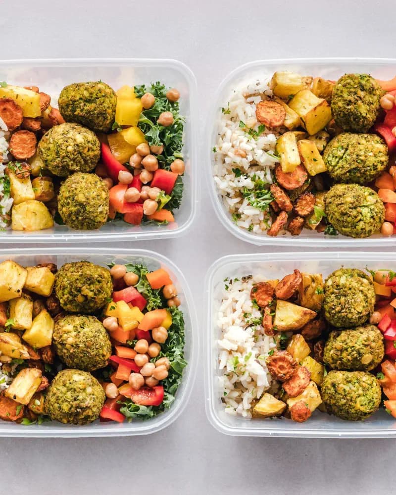 Quatro recipientes com arroz, legumes, grão-de-bico e bolinhos vegetais.