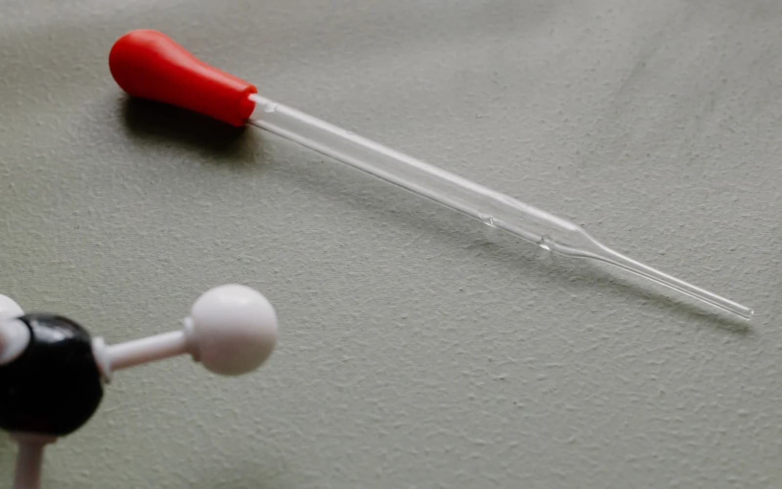 Conta-gotas, tubos de ensaio e modelos moleculares em bancada de laboratório.
